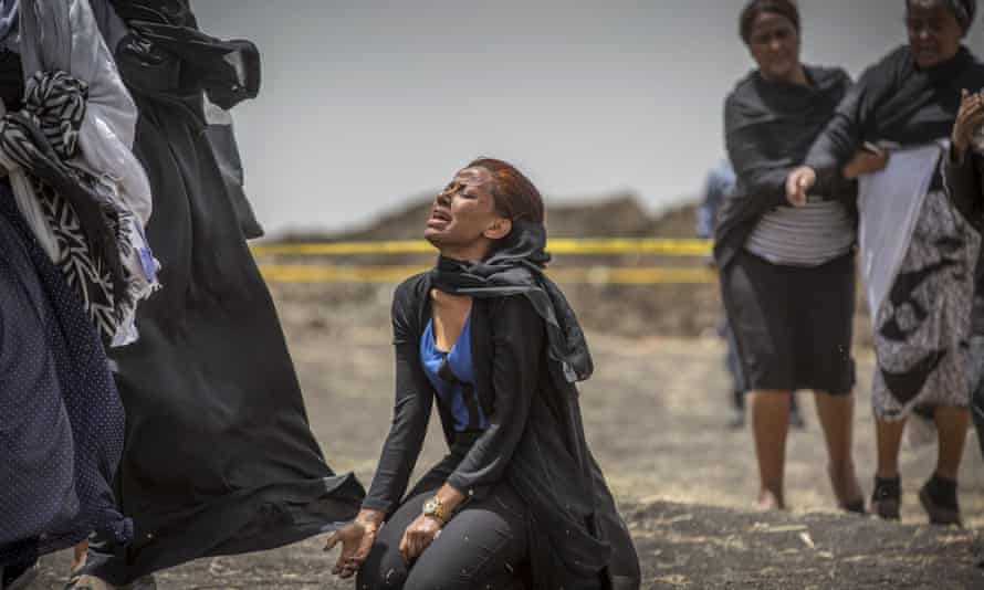 Woman on her knees, head thrown back in anguish. Two other women stand behind her