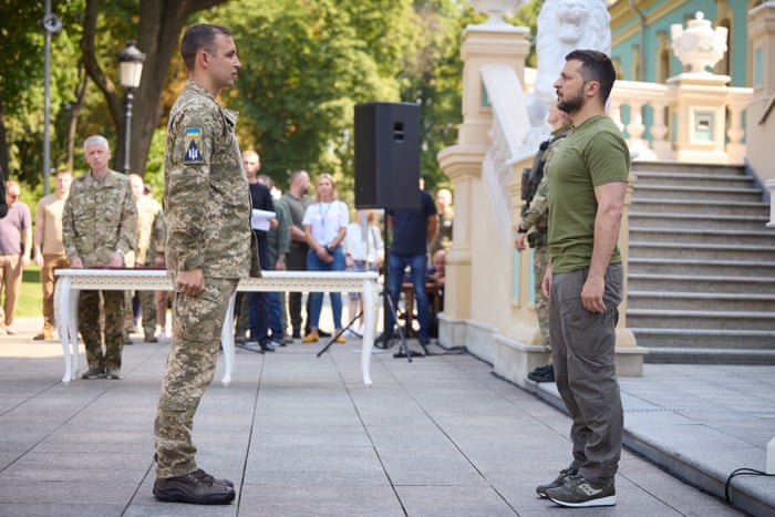 Handout picture taken and released by Ukrainian Presidential Press service shows the President Volodymyr Zelensky (R) presenting orders and the other state awards to the service personnel and to the members of the families of fallen soldiers in Kyiv on August 7, 2022, on the occasion of the of the Air Force of Ukraine Day.