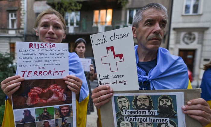 Protestors hold placards with images related to the Russian invasion of Ukraine and Mariupol defenders.