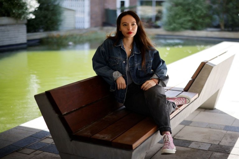 Soma Sara sitting on a bench by a water garden