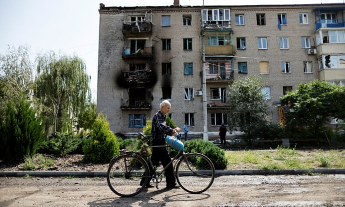 A Ukrainian man walks with his bicycle in front of damaged houses following recent Russian shelling in the city of Slovyansk. REUTERS/Ammar Awad