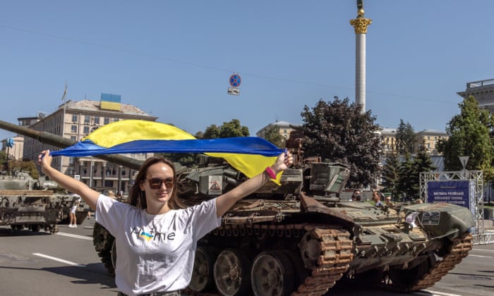 A woman holding a Ukrainian flag poses for photos next to Russian armoured military vehicles that were captured in fights by the Ukrainian army, displayed in Khreshchatyk street on Independence Day.