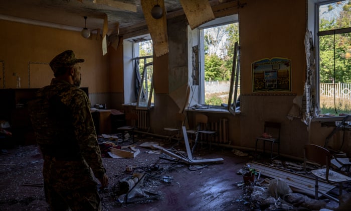 A Ukrainian soldier inspects damage to the school in Kharkiv after the missile strike