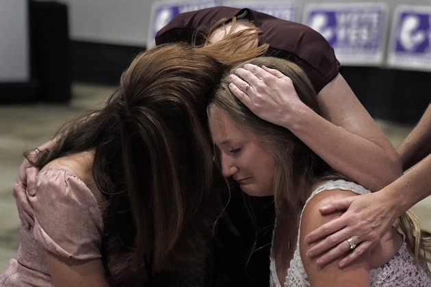 Three women hug and cry during a Value Them Both watch party.